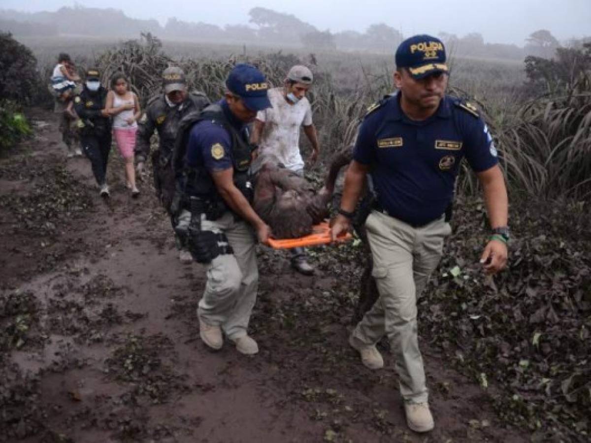 Police officers carry a wounded man after the eruption of the Fuego Volcano, in El Rodeo village, Escuintla department, 35 km south of Guatemala City on June 3, 2018. / AFP PHOTO / NOE PEREZ