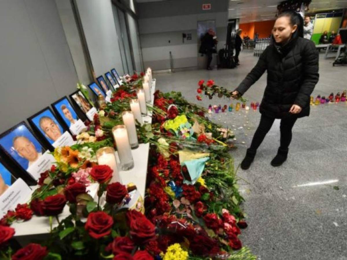 A woman places flowers at a memorial for the victims of the Ukraine International Airlines Boeing 737-800 crash in the Iranian capital Tehran, at the Boryspil airport outside Kiev on January 8, 2020. - A Ukrainian airliner crashed shortly after take-off from Tehran Wednesday killing all 176 people on board, in a disaster striking a region rattled by heightened military tensions. (Photo by Sergei SUPINSKY / AFP)