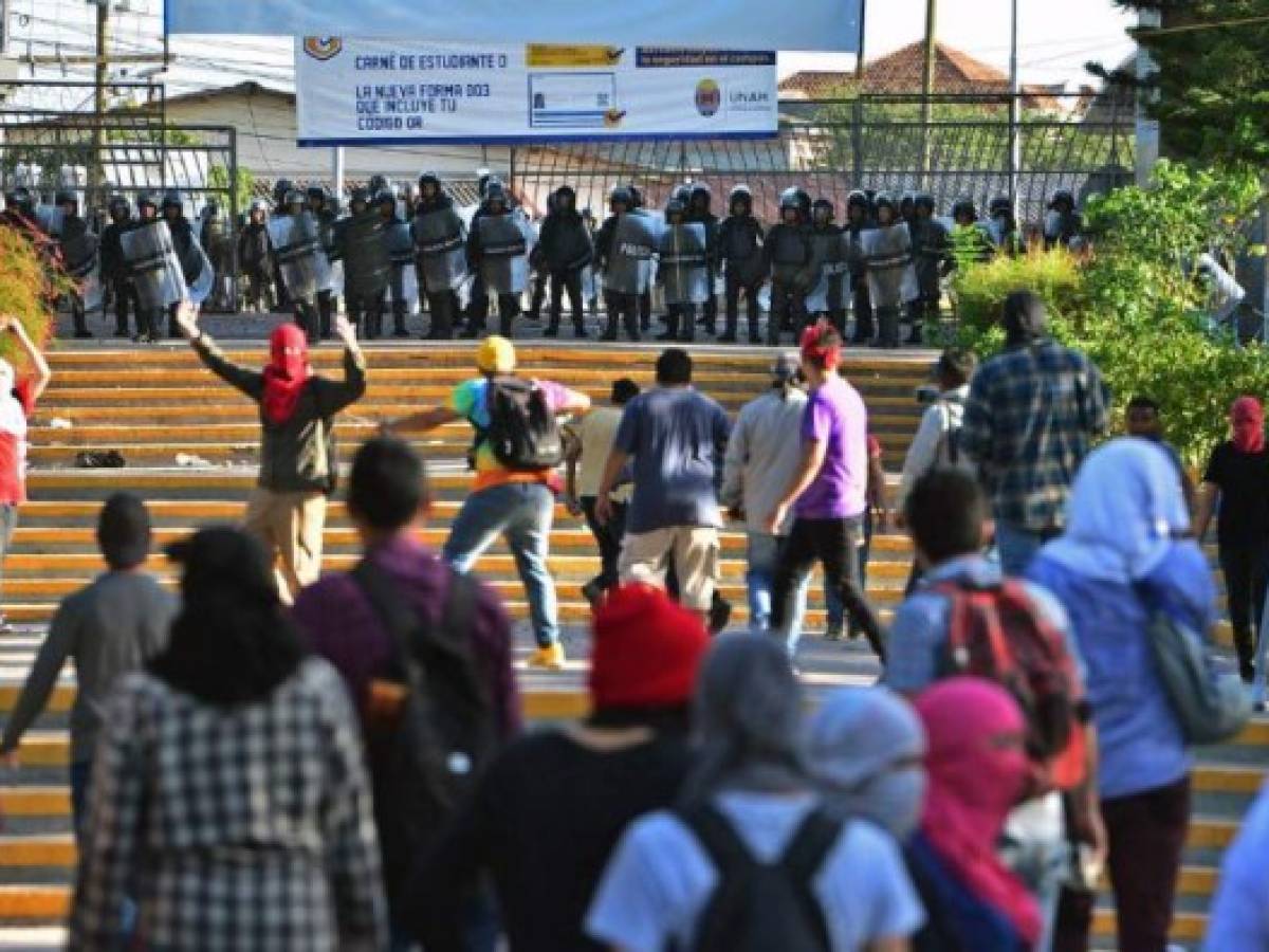 Students of the National Autonomous University of Honduras (UNAH) confront riot police during a protest against the goverment of Honduran President Juan Orlando Hernandez in Tegucigalpa on June 24, 2019. - Ongoing protests against Hernandez intensified last week after beginning more than a month ago when doctors and teachers unions held strikes against health and education laws. (Photo by ORLANDO SIERRA / AFP) Students of the National Autonomous University of Honduras (UNAH) confront riot police during a protest against the goverment of Honduran President Juan Orlando Hernandez in Tegucigalpa on June 24, 2019. - Ongoing protests against Hernandez intensified last week after beginning more than a month ago when doctors and teachers unions held strikes against health and education laws. (Photo by ORLANDO SIERRA / AFP)