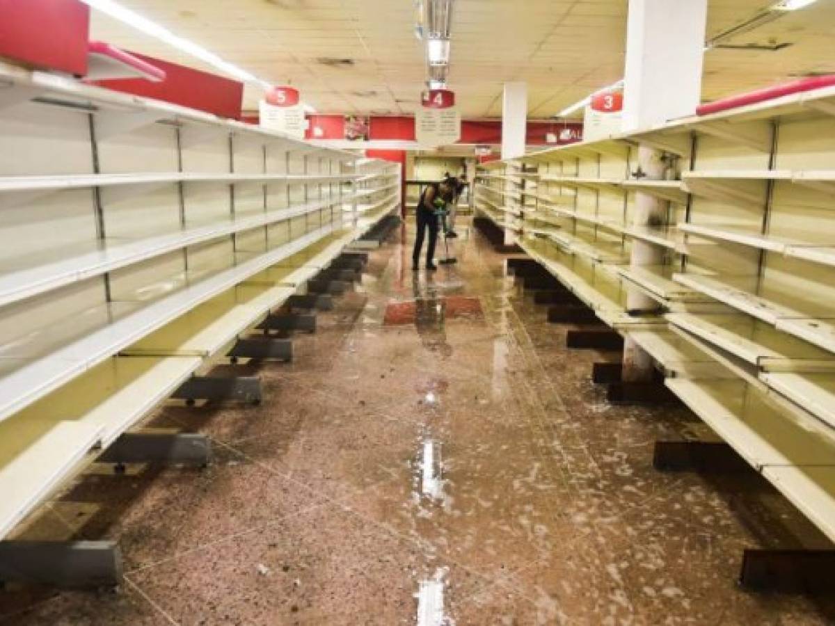 An employee cleans at a supermarket in Valencia, Carabobo State, on May 5, 2017, the day after anti-government protesters looted stores, set fire to cars and clashed with police, leaving at least five people injured, and one dead after being hit in the head by a projectile .The latest toll provided by prosecutors said 36 people have been killed in just over a month of protests against President Nicolas Maduro, whose opponents blame him for Venezuela's dire economic mess. / AFP PHOTO / RONALDO SCHEMIDT