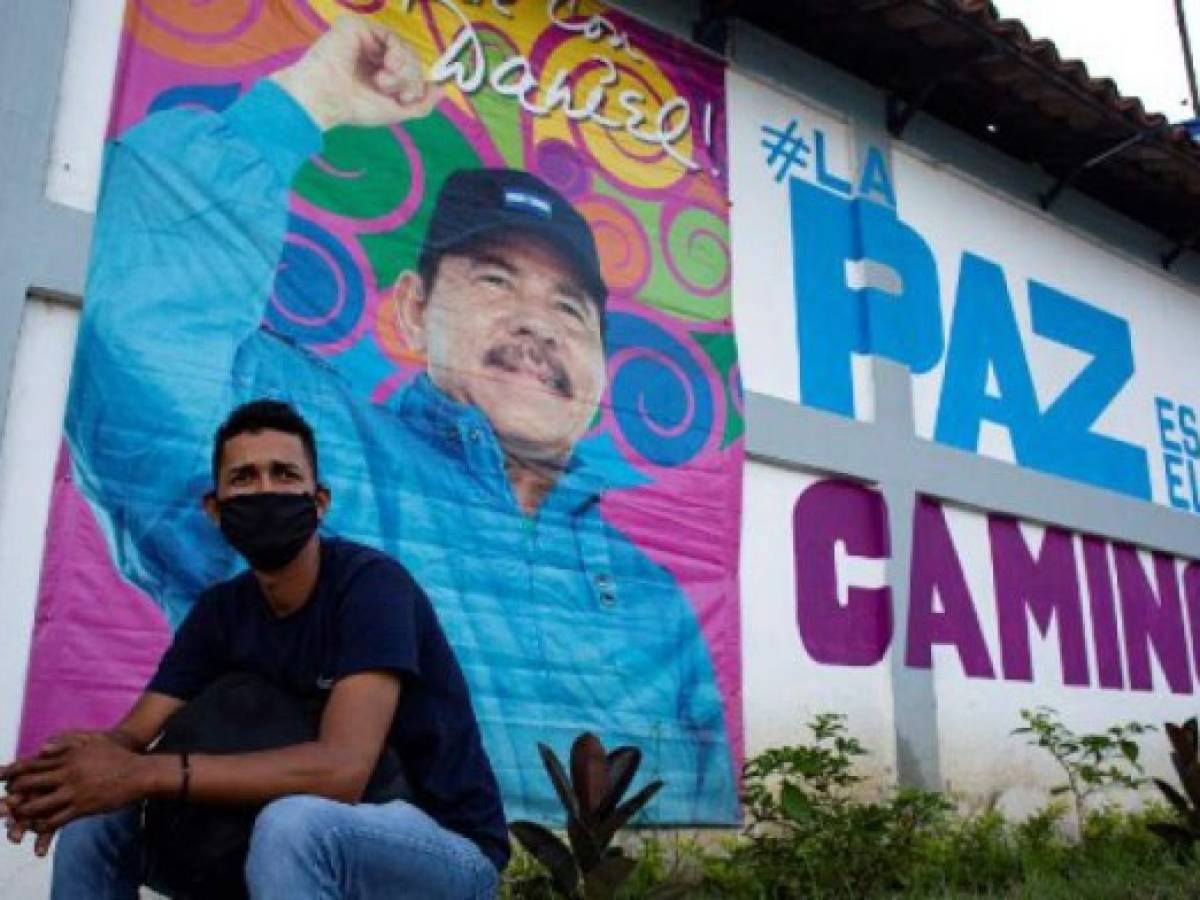 A man sits in front of a banner promoting Nicaragua's President Daniel Ortega candidacy in Managua on September 24, 2021. - Nicaragua officially kicks off campaigning for the 7 November presidential elections on Saturday, with President Daniel Ortega's main rivals arrested and the way clear for him to seek a fourth consecutive term in office. (Photo by OSWALDO RIVAS / AFP)