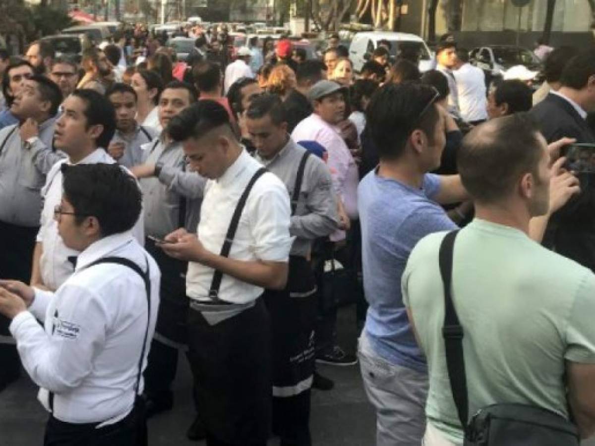 People stand in the street during a powerful earthquake in Mexico City on February 16, 2018.Mexico's National Seismological Service put the magnitude of the quake at 7.0, and seismic monitor network Sky Alert said the quake was felt across the states of Guerrero, Oaxaca and Puebla. / AFP PHOTO / PEDRO PARDO