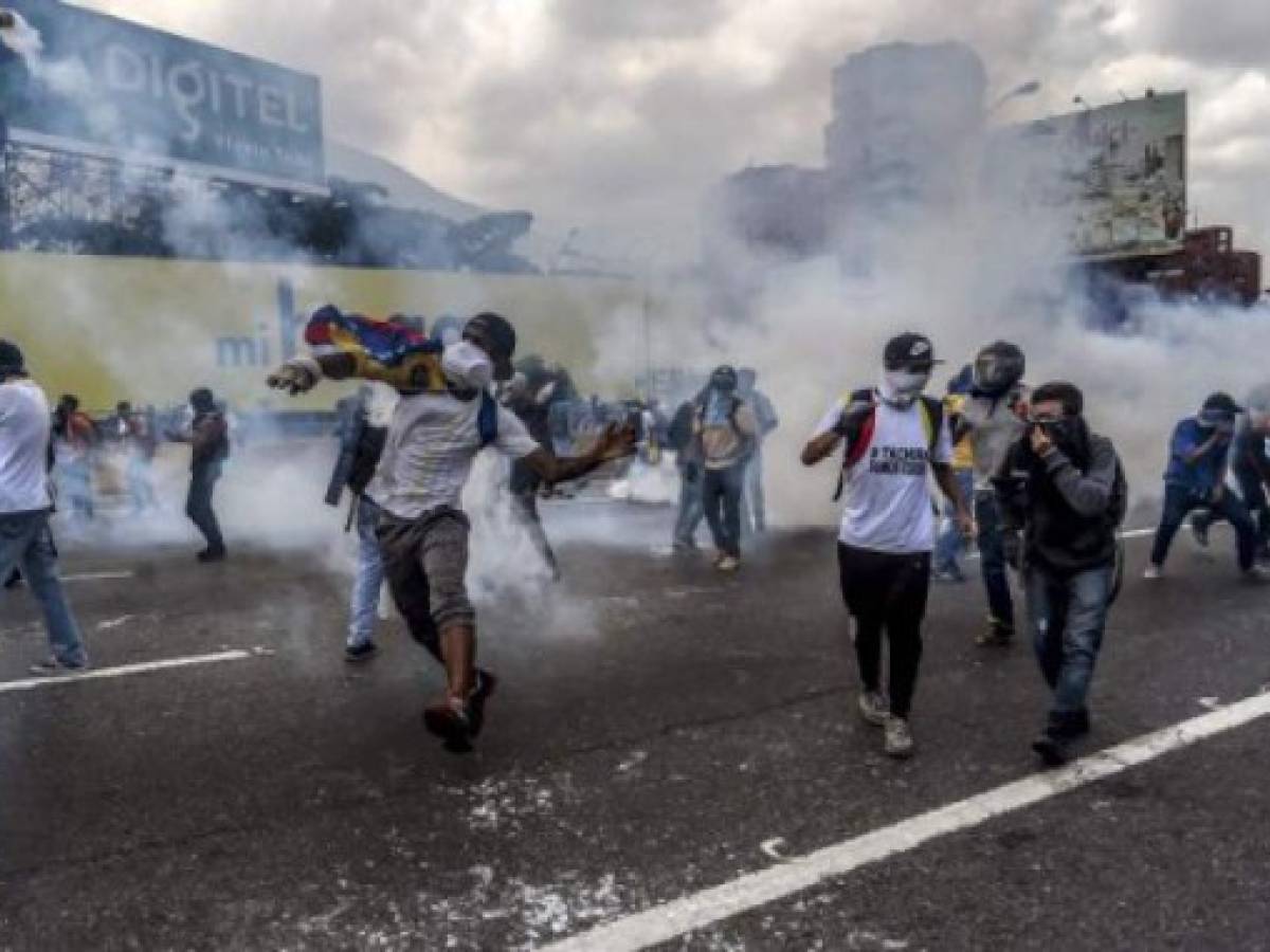 Opposition activists clash with riot police during a protest march in Caracas on April 26, 2017.Protesters in Venezuela plan a high-risk march against President Maduro Wednesday, sparking fears of fresh violence after demonstrations that have left 26 dead in the crisis-wracked country. / AFP PHOTO / JUAN BARRETO