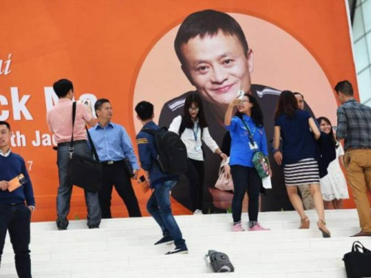 Estudiantes se fotografían frente a un afiche de Jack Ma, el hombre más rico de China, el cofundador de Alibaba Group en el Centro de Convenciones de Hanoi, Vietna, el 6 de noviembre de 2017. / AFP PHOTO / HOANG DINH NAM