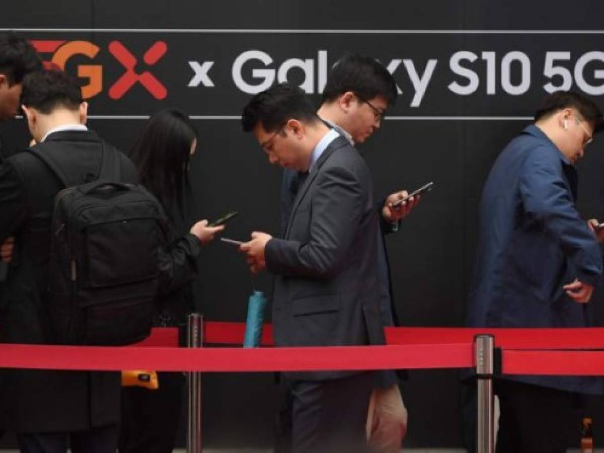 People wait in line to buy new Samsung Galaxy S10 5G smartphones in front of an SK Telecom shop during a launch event in Seoul on April 5, 2019. - The world's biggest smartphone and memory chip maker Samsung Electronics warned of a 60 percent-plus plunge in first-quarter operating profits on April 5, in the face of a weakening chip market. Samsung was also launching its top-end Galaxy S10 5G smartphone, after South Korea this week won the global race to commercially launch the world's first nationwide 5G networks. (Photo by JUNG Yeon-Je / AFP)