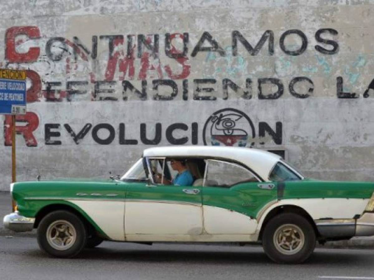 A car drives past a wall reading 'We Continue Defending Revolution' referring to Committees for the Defense of the Revolution (CDR), in Havana on March 20, 2018.The CDR, which were created by Cuban late leader Fidel Castro in 1960 as surveillance and unconditionality symbols, will remain as community spaces after Raul Castro leaves Cuba's presidency. / AFP PHOTO / Yamil LAGE / TO GO WITH AFP STORY BY MOISES AVILA AND CARLOS BATISTA A car drives past a wall reading 'We Continue Defending Revolution' referring to Committees for the Defense of the Revolution (CDR), in Havana on March 20, 2018.The CDR, which were created by Cuban late leader Fidel Castro in 1960 as surveillance and unconditionality symbols, will remain as community spaces after Raul Castro leaves Cuba's presidency. / AFP PHOTO / Yamil LAGE / TO GO WITH AFP STORY BY MOISES AVILA AND CARLOS BATISTA