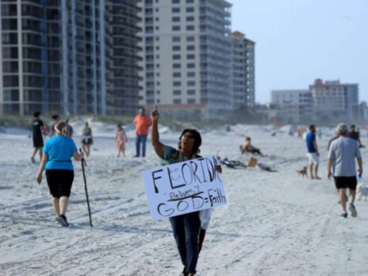JACKSONVILLE BEACH, FLORIDA - APRIL 17: A person carries a sign at the beach on April 17, 2020 in Jacksonville Beach, Florida. Jacksonville Mayor Lenny Curry announced Thursday that Duval County's beaches would open at 5 p.m. but only for restricted hours and can only be used for swimming, running, surfing, walking, biking, fishing, and taking care of pets. (Photo by Sam Greenwood/Getty Images)