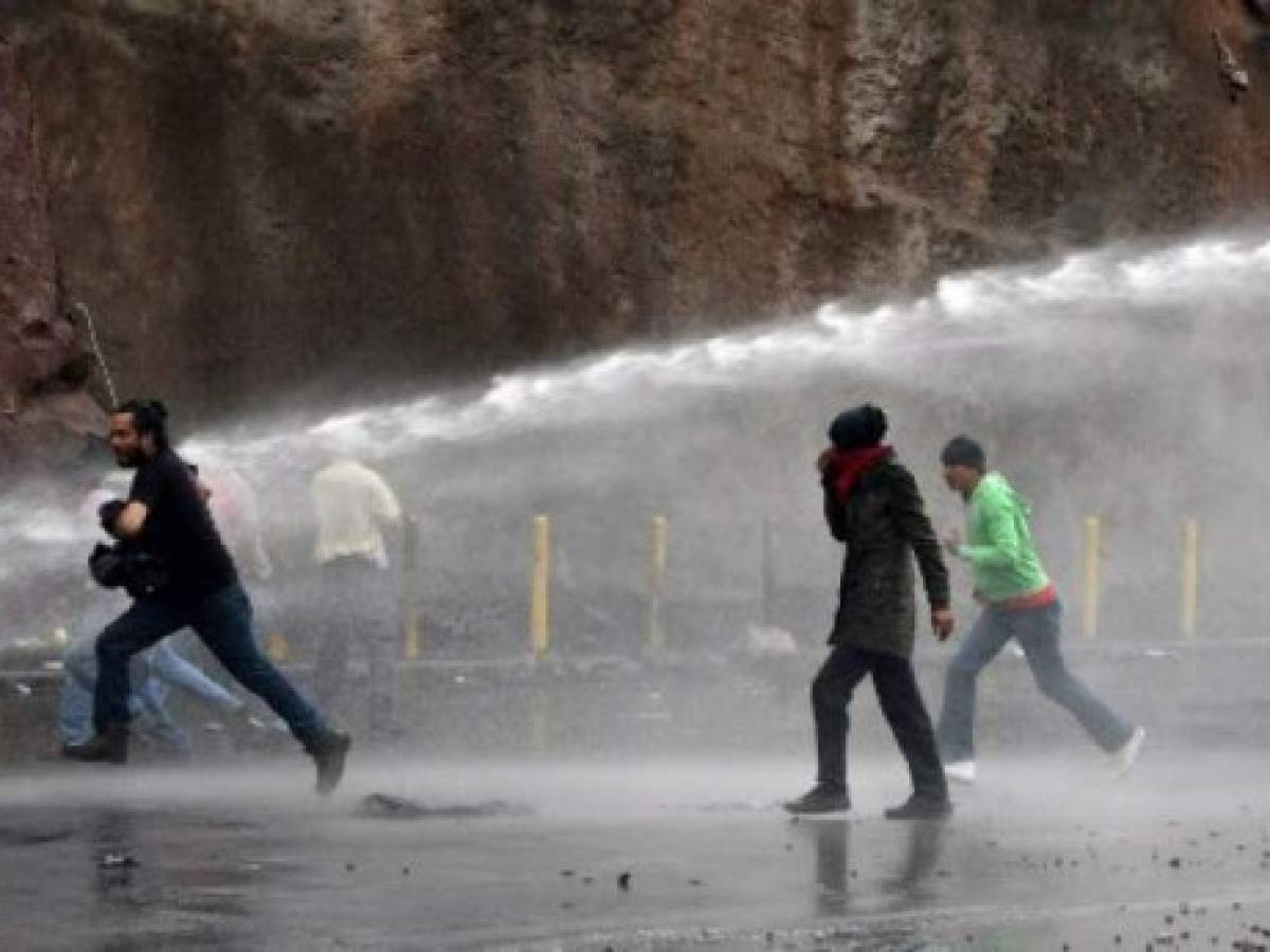 Riot police officers use a water cannon to disperse supporters of opposition candidate Salvador Nasralla during protests in Tegucigalpa, on December 18, 2017.Honduran President Juan Orlando Hernandez is declared the winner of a heavily disputed presidential election held three weeks ago, despite mounting protests and opposition claims of fraud. / AFP PHOTO / ORLANDO SIERRA Riot police officers use a water cannon to disperse supporters of opposition candidate Salvador Nasralla during protests in Tegucigalpa, on December 18, 2017.Honduran President Juan Orlando Hernandez is declared the winner of a heavily disputed presidential election held three weeks ago, despite mounting protests and opposition claims of fraud. / AFP PHOTO / ORLANDO SIERRA