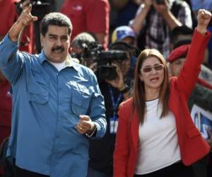 Venezuelan President Nicolas Maduro (L) and First Lady Cilia Flores (R) greet supporters during a rally in Caracas on January 23, 2018.Venezuela's Maduro says he is ready to run for a second term. / AFP PHOTO / JUAN BARRETO
