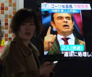 Pedestrians walk past a television screen showing a news programme featuring former Nissan chief Carlos Ghosn in Tokyo on November 30, 3018. - A Tokyo court on November 30 extended the detention of former Nissan chief Carlos Ghosn, local media said, after his arrest on allegations of financial misconduct that have shaken the auto industry. (Photo by Kazuhiro NOGI / AFP)
