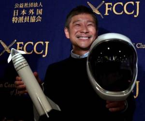 Yusaku Maezawa, entrepreneur and CEO of ZOZOTOWN and SpaceX BFR's first private passenger, poses with a miniature rocket and space helmet prior to start of a press conference at the Foreign Correspondents' Club of Japan in Tokyo on October 9, 2018.It was confirmed in September that Maezawa will be the first man to fly around the moon on a SpaceX rocket as early as 2023. / AFP PHOTO / Toshifumi KITAMURA