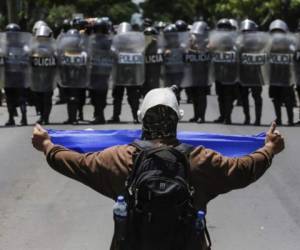 A masked demonstrator shows a nicaraguan flag to a line of riot police blocking a street during a protest against Nicaraguan President Daniel Ortega's government in Managua, on September 16, 2018. (Photo by INTI OCON / AFP)
