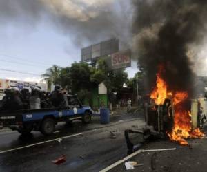 National Police officers in riot gear drive next to an overturned burning police vehicle, after an anti-government protest in Managua, on September 2, 2018. At least two people were injured on Sunday, when alleged paramilitaries fired against an opposition march, which ended up in violence in eastern Managua. / AFP PHOTO / INTI OCON