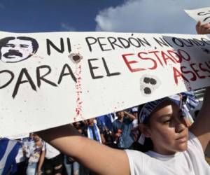 A student holds a sign reading Neither forgiveness nor forgetfulness for the murderous state during a march marking a month since the beginning of protests against the government in Managua on May 18, 2018. The Inter-American Commission on Human Rights on Friday called for Nicaragua's government to 'immediately halt the repression of protests' against President Daniel Ortega, as the death toll rose to 63. / AFP PHOTO / DIANA ULLOA