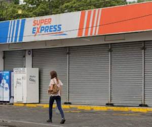 A woman passes by a closed supermarket during a national strike called by the opposition Civic Alliance in Managua on May 23, 2019. - Nicaragua's opposition called a 24-hour general strike to increase pressure on the government of President Daniel Ortega to release prisoners as agreed in peace talks between the two sides. (Photo by INTI OCON / AFP)