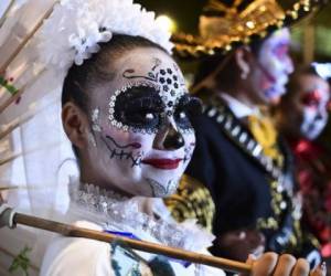 People fancy dressed as 'Catrina' take part in the 'Catrinas Parade' along Reforma Avenue, in Mexico City on October 22, 2017. Mexicans get ready to celebrate the Day of the Dead highlighting the character of La Catrina which was created by cartoonist Jose Guadalupe Posada, famous for his drawings of typical local, folkloric scenes, socio-political criticism and for his illustrations of 'skeletons' or skulls, including La Catrina. / AFP PHOTO / RONALDO SCHEMIDT