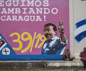 Men rest next to a graffiti of Nicaraguan President Daniel Ortega in Esteli, about 150 km from Managua, on December 27, 2018. - Ortega first came to power in 1979 as a leader of the leftist Sandinista rebels that toppled the US-backed Somoza family dictatorship. After leaving office in 1990 he returned to power in 2007. Rights groups say at least 320 people have been killed in Nicaragua in a brutal government crackdown launched in response to the escalation in April 2018 of street protests, initially against a now-ditched pension reform. (Photo by Inti OCON / AFP)