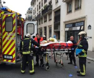 Unos bomberos evacuan a un herido en camilla ante las oficinas del semanario satírico francés Charlie Hebdo, este miércoles 7 de enero en París. (Foto: AFP)
