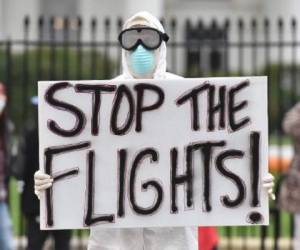 'Paren los vuelos' dice el cartel de un hombre vestido con un traje de protección ante la Casa Blanca. (Foto: AFP).