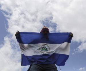A demonstrator holds a Nicaraguan national flag, during a march against President Daniel Ortega's government in Managua, on September 2, 2018. At least two people were injured on Sunday, when alleged paramilitaries fired against an opposition march, which ended up in violence in eastern Managua. / AFP PHOTO / INTI OCON