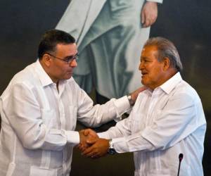 <i>ARCHIVO. El expresidente de El Salvador Mauricio Funes (izquierda) le da la mano al expresidente Salvador Sánchez Cerén (derecha) durante una reunión del equipo de transición del gobierno en San Salvador el 17 de marzo de 2014. FOTO AFP/ José CABEZAS </i>