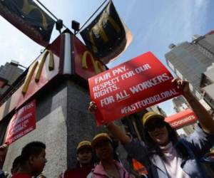 Empleados de cadenas de comida rápida protestan frente a un restaurante McDonald's.