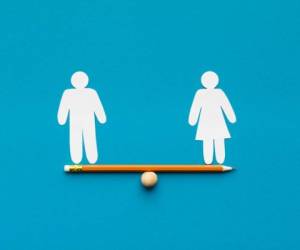 Gender equality in corporate world. Figures of man and woman on pencil seesaw, blue background, copy space