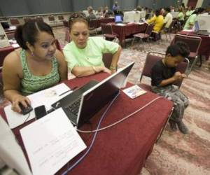 Lilibeth Moronta-Mueses (izquierda) se anota para el seguro de desempleo con la ayuda de una voluntaria, Nydia Rodas, el 3 de setiembre de 2014 en un centro de convenciones en Atlantic City. (Foto: AFP)