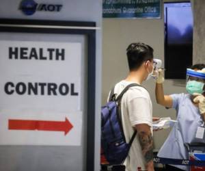 A health official checks the temperature of an incoming passenger during a health assessment at a checkpoint for people flying in from a list of countries and territories that include China, Hong Kong, Macau, South Korea, Iran and Italy, as a precautionary measure against the spread of the COVID-19 coronavirus at Suvarnabhumi Airport in Bangkok on March 9, 2020. (Photo by VIVEK PRAKASH / AFP)