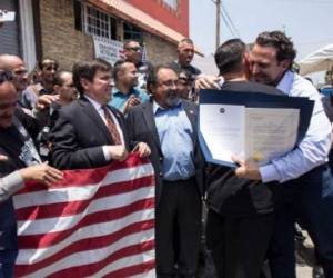 Human Rights Chair Nathan Fletcher (R) greets Mexican deported veteran Erasmo Apodaca and hands him his Pardon papers granted by California Gov. Jerry Brown, while other US Congress members look on, outside the Deported Veterans Support House in Tijuana, Mexico, on June 3 2017. Seven members of Congress visit the Deported Veterans Support House in Tijuana, Mexico to meet with veterans who have been deported from the United States. / AFP PHOTO / GUILLERMO ARIAS
