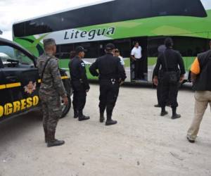 Guatemalan national civil police agents prepare to inspect a bus in Guastatoya, El Progreso department, Guatemala, on October 24, 2018. - Thousands of Central American migrants crossing Mexico toward the United States in a caravan resumed their long trek Wednesday with a day's walk expected to take about 12 hours. (Photo by ORLANDO ESTRADA / AFP)