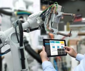 Engineer hand using tablet, heavy automation robot arm machine in smart factory industrial with tablet real time monitoring system application. Industry 4th iot concept.