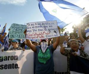 A student holds a sign reading 'If there is no justice for the people, let there not be peace for the government' during a march marking a month since the beginning of protests against the government in Managua on May 18, 2018. The Inter-American Commission on Human Rights on Friday called for Nicaragua's government to 'immediately halt the repression of protests' against President Daniel Ortega, as the death toll rose to 63. / AFP PHOTO / DIANA ULLOA