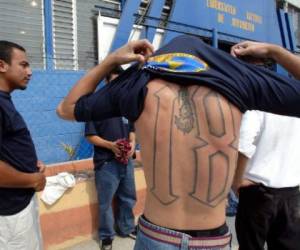 Integrantes de la mara (pandilla) 'M-18' se cambian de ropa para cubrir sus tatuajes en abril de 2005, antes de su ingreso a la Iglesia Tabernaculo Biblico de Avivamiento, en San Bartolo, El Salvador. AFP PHOTO / YURI CORTEZ