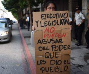 A woman holds a sign reading 'The Executive and Legislative cannot abuse of the power given to them by the people' while demonstrating outside the National Congress in Guatemala City on September 5, 2018.The head of the International Commission Against Impunity in Guatemala (CICIG), Colombian Ivan Velasquez will continue to direct its work from outside the country after he was barred from re-entering by President Jimmy Morales' government. / AFP PHOTO / JOHAN ORDONEZ