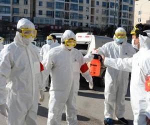 This photo taken on February 18, 2020 shows members of a police sanitation team having their protective suits disinfected after they sprayed disinfectant in the streets as a preventive measure against the spread of the COVID-19 coronavirus in Bozhou, in China's eastern Anhui province. - The death toll from China's new coronavirus epidemic jumped past 2,000 on February 19 after 136 more people died, with the number of new cases falling for a second straight day, according to the National Health Commission. (Photo by STR / AFP) / China OUT