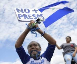 An anti-government protester who wants President Daniel Ortega and his powerful vice president, wife Rosario Murillo to resign, holds a placard reading 'No More Prisoners' as he marches demanding justice for doctors dismissed from a public hospital for treating protesters wounded in demonstrations, in Managua on August 4, 2018.More than a dozen doctors, nurses and technical staff in a public hospital in Nicaragua have been sacked in July because they treated wounded anti-government protesters and were seen backing their cause, medical sources said. / AFP PHOTO / Marvin RECINOS