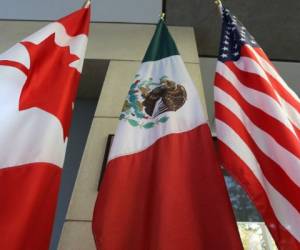 (FILES) In this file photo taken on September 24, 2017 the Mexican, US and the Canadian flags sit in the lobby where the third round of the NAFTA renegotiations are taking place in Ottawa, Ontario. Canadian and US negotiators reached a deal late on September 30, 2018 on reforming the North American Free Trade Agreement (NAFTA), Canadian media reported. / AFP PHOTO / Lars Hagberg