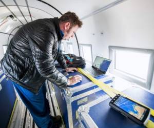 Joshua Willis, head of Oceans Melting Greenland, or OMG, prepares to drop a 1.5-metre cylindrical probe onboard the refitted DC3, built in 1942 for the Canadian air force during World War II, on August 15, 2019 flying along the eastern cost of Greenland. - On board an old restored cuckoo plane razing the white desert of East Greenland, three NASA scientists drop probes into the pearly waters of the Arctic to measure the impact of the oceans on ice melt. (Photo by Jonathan NACKSTRAND / AFP) / TO GO WITH AFP STORY BY Tom LITTLE