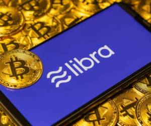 Gold Bitcoin Coins pile with the Facebook's Libra Crypto Coin logo on smartphone screen