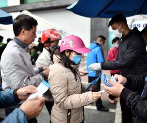 Vietnamese residents queue to receive free protective facemasks at a make-shift distribution centre amid concerns of the novel coronavirus outbreak, in Hanoi on February 8, 2020. - Nearly 35,000 people have been infected by the new virus strain, which is believed to have emerged in a market selling wild animals in Wuhan last year before spreading across China and nearly 30 other countries. (Photo by Manan VATSYAYANA / AFP)