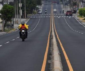 A fast food delivery motorcyclist rides along an empty street after the government decreed new measures to prevent the spread of the new cortonavirus suspending the circulation of all public and private collective transport in San Salvador in May 7, 2020. (Photo by Yuri CORTEZ / AFP)