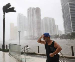 MIAMI, FL - SEPTEMBER 10: A person battles high winds and rain after taking pictures of the flooding along the Miami River as Hurricane Irma passes through on September 10, 2017 in Miami, Florida. Hurricane Irma made landfall in the Florida Keys as a Category 4 storm on Sunday, lashing the state with 130 mph winds as it moves up the coast. Joe Raedle/Getty Images/AFP