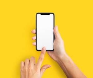 Mockup of female hands touching cell phone with blank screen on yellow background.