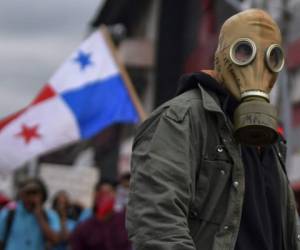 A demonstrator wearing a gas mask looks on during clashes with riot police during a protest of students, members of civil society organizations and unions against proposed constitutional reforms, outside of the Congress building in Panama City, on October 30, 2019. - The reform would include privatizing higher education and giving Congress more power. (Photo by Luis ACOSTA / AFP)