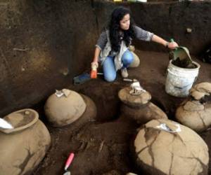 An employee of the Nicaraguan Institute of Culture (INC) worksnext to some 30 1,200-year-old pieces which were found in the surroundings of the construction site of the new National Baseball Stadium in Managua on June 20, 2017. / AFP PHOTO / INTI OCON