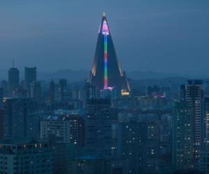 A North Korean flag is displayed in lights atop the empty Ryugyong hotel amid the Pyongyang city skyline on April 12, 2018.There has been no official word on any plans for the hotel -- although this weekend's 106th anniversary of Kim Il Sung's birth could be the occasion for some kind of unveiling. / AFP PHOTO / Ed JONES