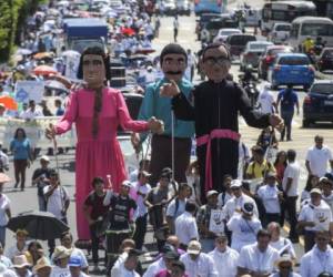 Demonstrators carry giant puppets representing blessed Salvador Archbishop Oscar Romero (R) and the Salvadoran people, during a protest against a water privatization bill under consideration of lawmakers in San Salvador, on September 27, 2018. / AFP PHOTO / MARVIN RECINOS