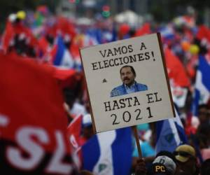 Un simpatizante del presidente de Nicaragua, Daniel Ortega, sostiene el rótulo 'Vamos a las elecciones hasta el 2021' / AFP PHOTO / Marvin RECINOS