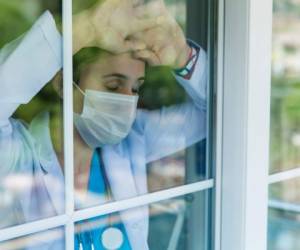 Worried female doctor looking through the hospital window